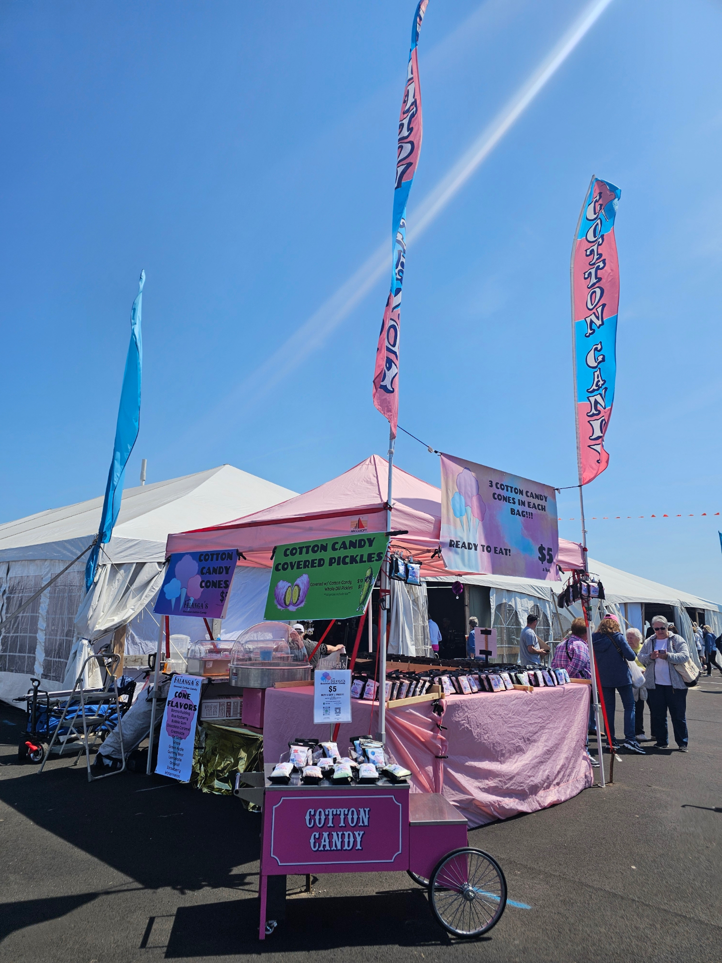 Falanga's Cotton Candy booth with pink and blue flags at an outdoor festival