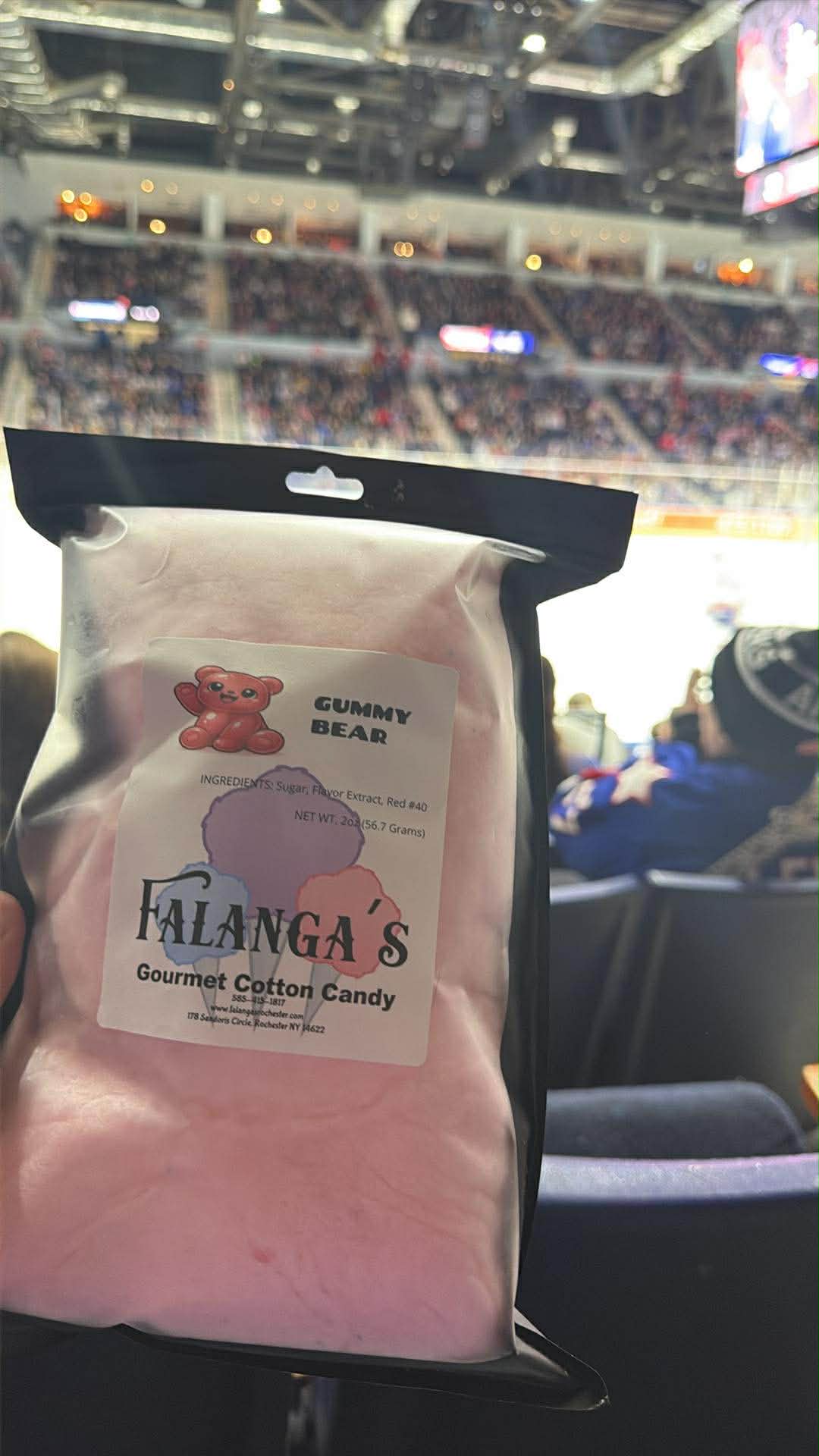 Fans holding pink cotton candy in a packed hockey arena