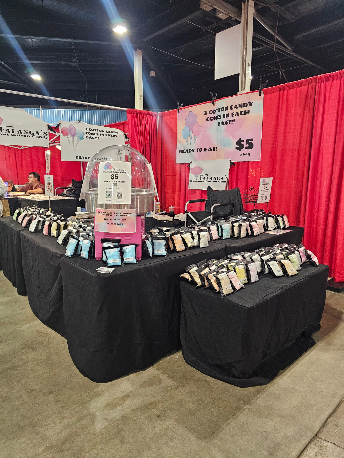 Tables full of pre-spun gourmet cotton candy bags at an indoor expo